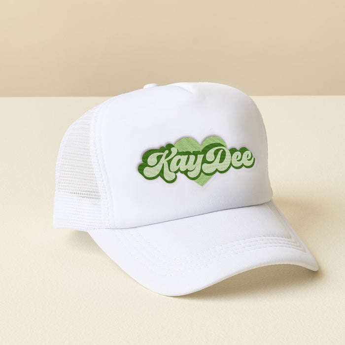 The Darling Effect's Kappa Delta White Trucker Hat features a green retro KayDee logo outlined by a heart—perfect for showing off your sisterhood style.