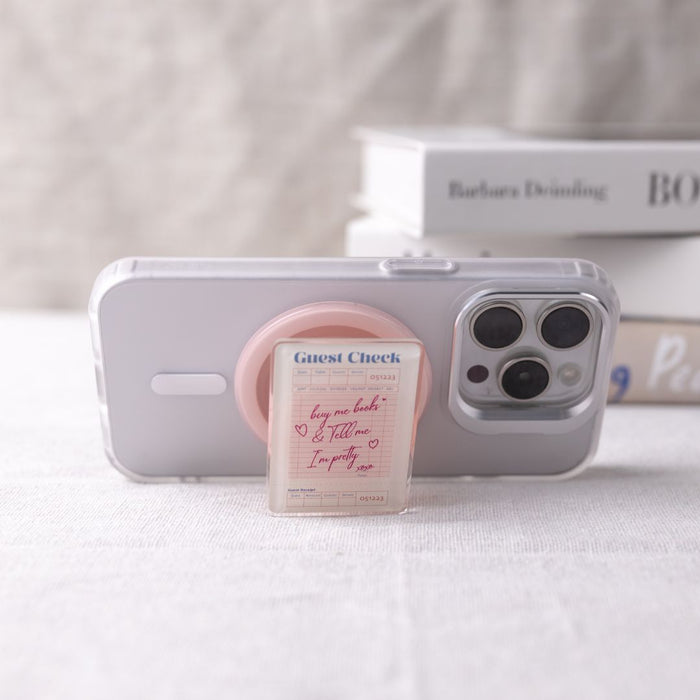 Phone with a pink stand and small box on a white surface