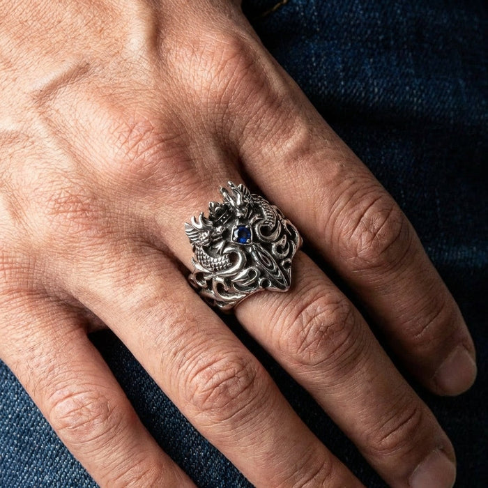 925 sterling silver dragon and sword ring with blue CZ stone worn on man's hand against denim background