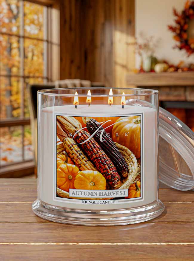 Kringle Candle Autumn Harvest candle on a wooden surface with fall decorations in the background