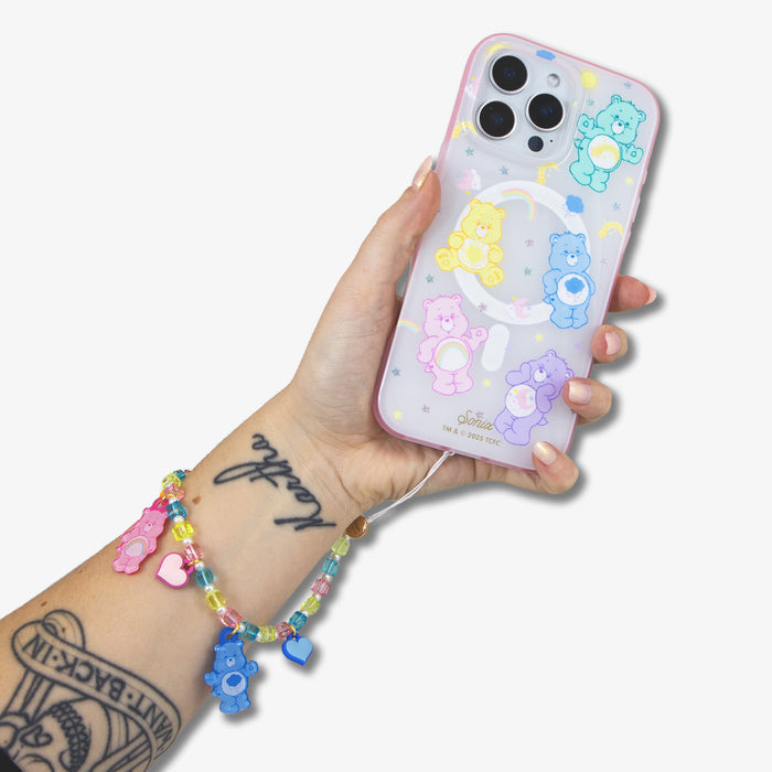 Close-up of beaded wristlet with multicolor beads and Care Bears charms looped on a hand holding a pastel iPhone case on white background