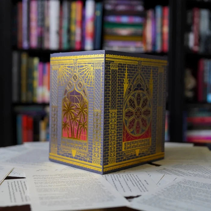 Bloodlines Special Edition Box Set by Richelle Mead – closed collector's box featuring gold architectural and palm tree foil illustrations on a navy blue background, displayed on manuscript pages