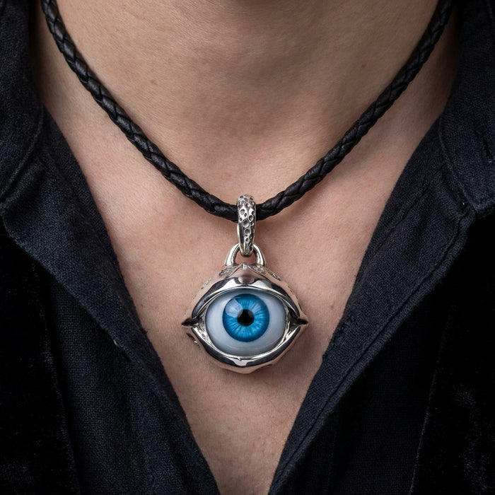 Blue eyeball pendant with silver claw setting on black braided leather cord necklace worn on model's neck, gothic biker jewelry style
