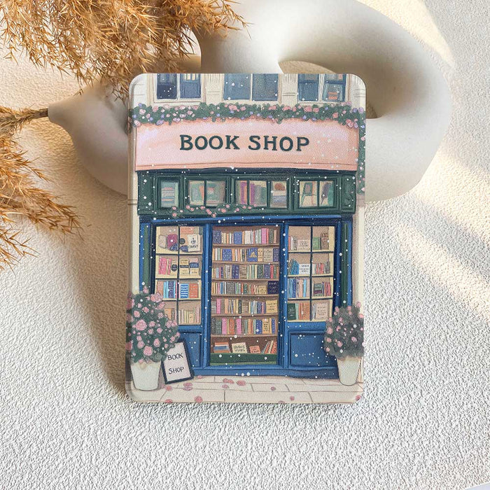 A Kindle case featuring a printed design of a bookshop with books and a store front.