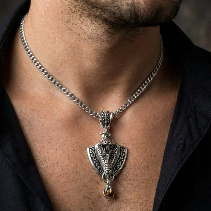 Man wearing sterling silver cobra shield pendant on Cuban chain with open collar black shirt