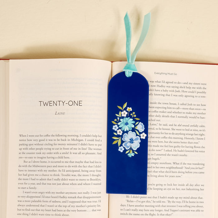 An open book displays a chapter titled TWENTY-ONE with the-darling-effect’s Dainty Floral Navy Acrylic Bookmark, featuring painted blue and white flowers and a velvet ribbon tassel—an enchanting gift for book lovers resting on the right page.