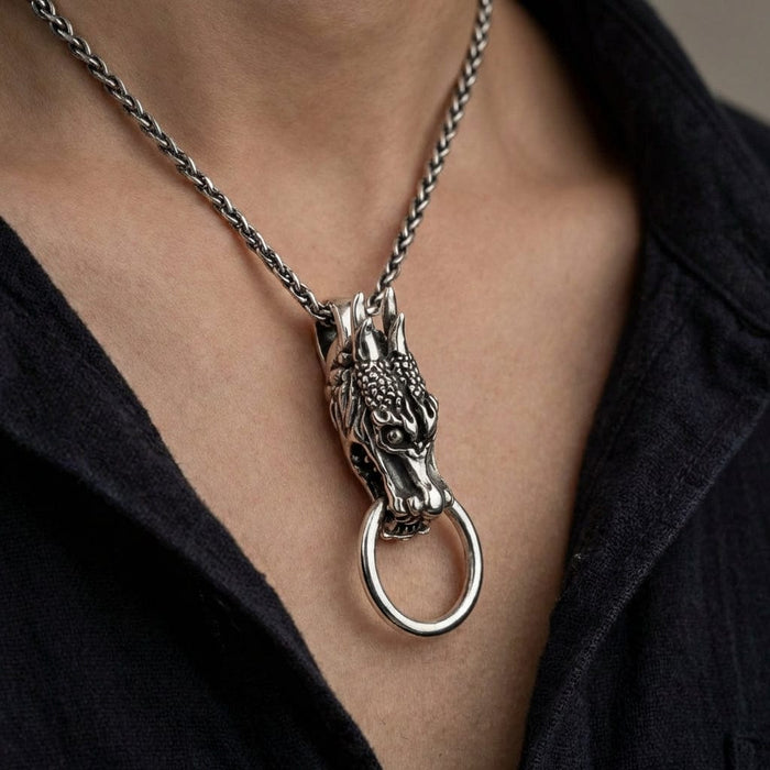 The sterling silver Eastern dragon pendant and its ring worn on a thick wheat chain against a man's chest.
