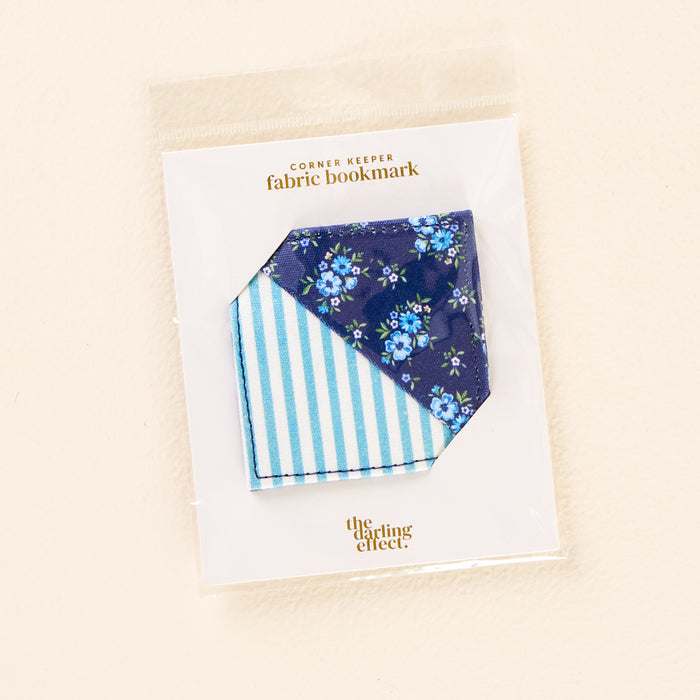 The Endless Daydream Navy Corner Keeper Fabric Bookmark by the-darling-effect features a blue floral side and a blue-and-white striped reverse—a charming packaged gift for book lovers.