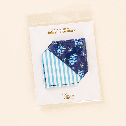 The Endless Daydream Navy Corner Keeper Fabric Bookmark by the-darling-effect features a blue floral side and a blue-and-white striped reverse—a charming packaged gift for book lovers.
