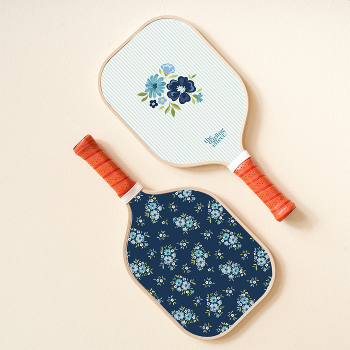 The Endless Daydream Navy Pickleball Paddle by the-darling-effect is shown on a light tan background, featuring a navy blue floral print—ideal for players seeking top-quality, stylish pickleball gear.
