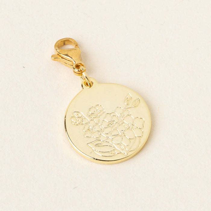 The February Jewelry Birth Flower Charm Gold by the-darling-effect features a gold circular pendant with floral engraving and a lobster clasp, making it a meaningful personalized accessory for those who love unique jewelry.