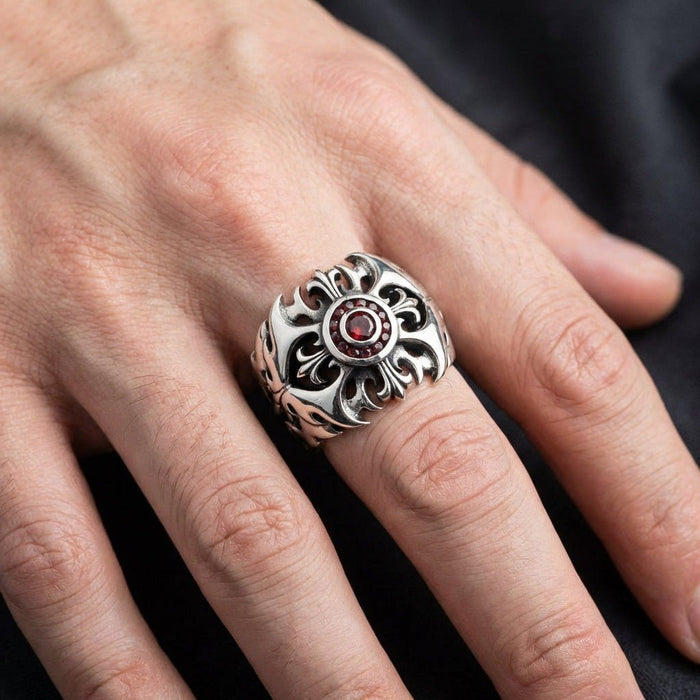 Handcrafted 925 sterling silver ring with red garnet center and ornate fleur-de-lis cross design worn on a man's finger