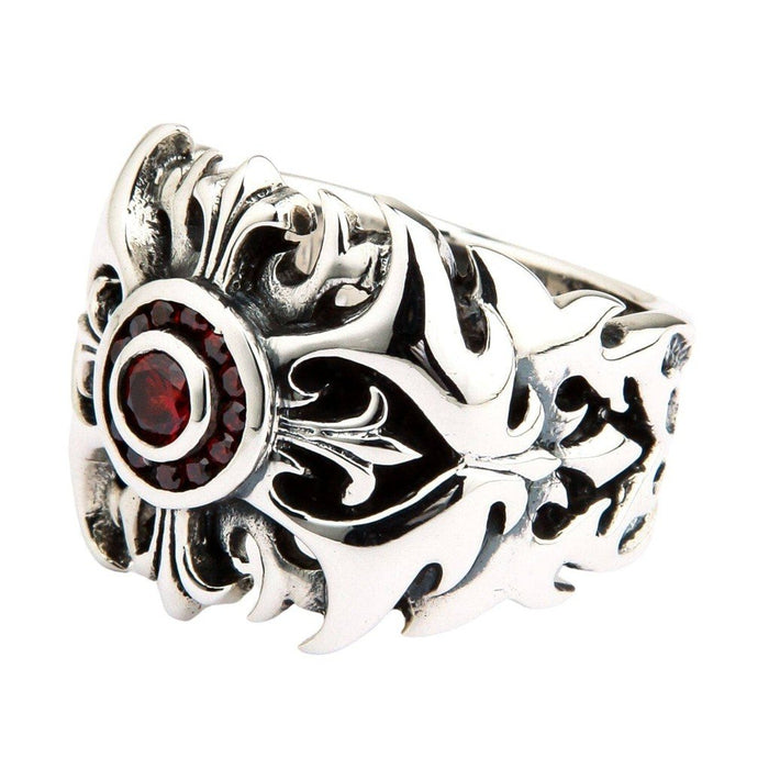 Angled close-up of sterling silver tribal ring showcasing red garnet stones in circular bezel with flowing floral scroll work