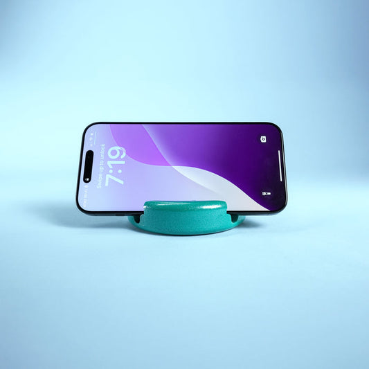 Smartphone on a turquoise stand against a light blue background
