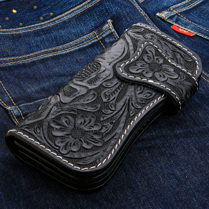 The hand-tooled floral pattern side of the black leather biker wallet, shown on denim.