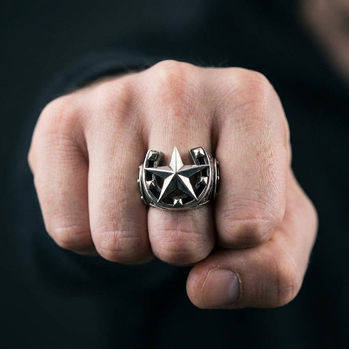 Sterling silver horseshoe star signet ring worn on middle finger showing bold nautical star design in fist pose