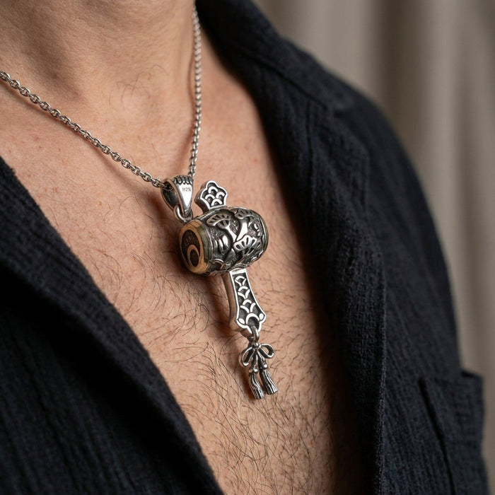 Lifestyle shot showing the carved silver Japanese gavel necklace worn on a chain against a black shirt.