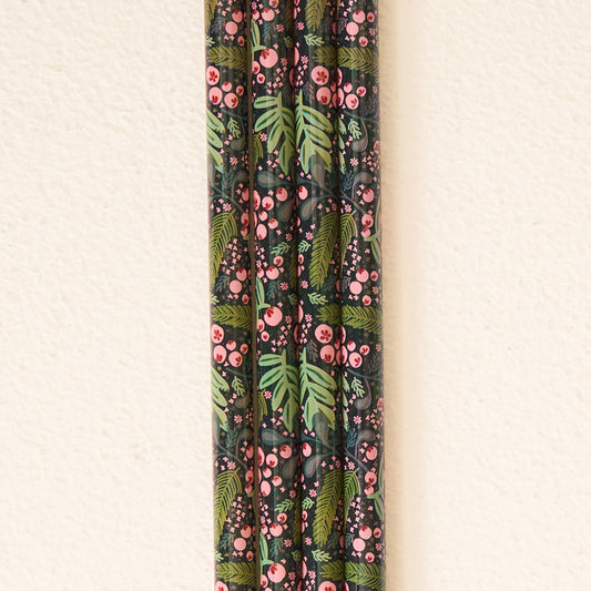 Five Jolly Sprig Green 40 oz Tumbler Straw Sets from The Darling Effect, featuring a dark floral pattern with pink berries and green leaves, are arranged vertically against an off-white textured wall, adding an eco-friendly touch to your drinkware collection.
