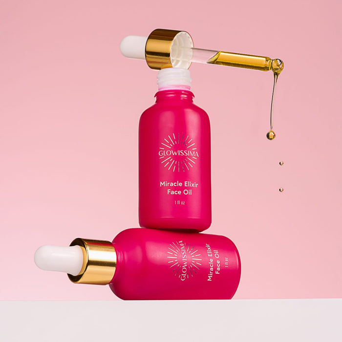 Pink face oil bottle with dropper on a pink background