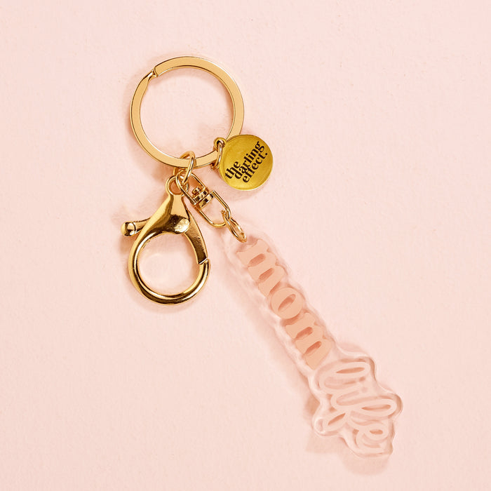 The Mom Life Acrylic Keychain by the-darling-effect features a charming "Mom" design with a gold disk, making it a sweet and stylish addition to any keychain collection.