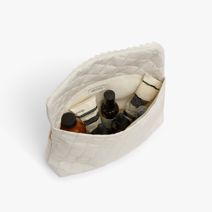 Cream | Top interior view of Monos x Reformation cosmetic pouch with in cream with products inside