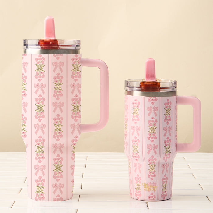 Two Oh So Fancy Pink 40 oz Lifestyle Flip Straw Tumblers by the-darling-effect feature a floral and bow pattern, pink handle, pink lid, matching straw, and leak-resistant design—perfect for your stylish drinkware collection.