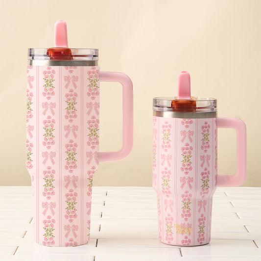 Two Oh So Fancy Pink 40 oz Lifestyle Flip Straw Tumblers by the-darling-effect feature a floral and bow pattern, pink handle, pink lid, matching straw, and leak-resistant design—perfect for your stylish drinkware collection.