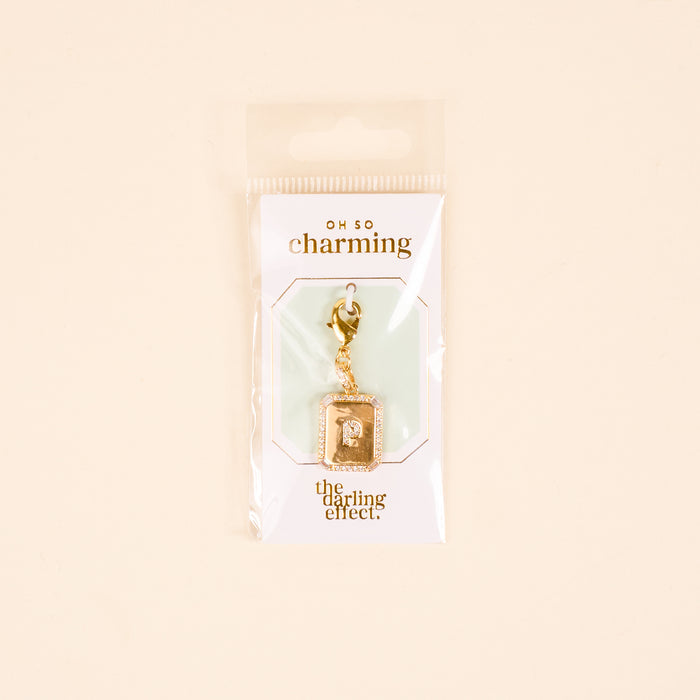 The P Jewelry Charm Initial Letter Gold by the-darling-effect is a gold-plated brass lock-shaped charm on a white card with gold "OH SO charming" and "the darling effect" text, packaged in a clear bag—ideal for personalized jewelry.