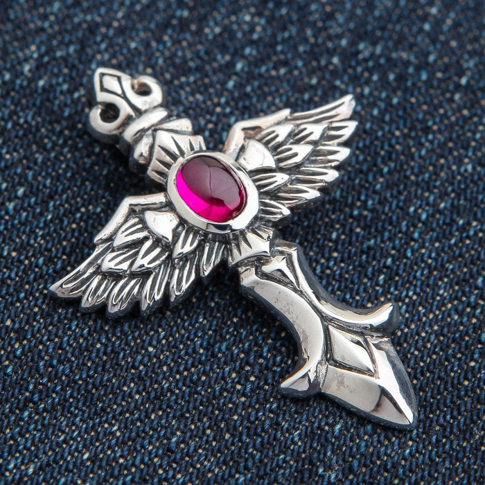 An angled view of the gothic winged sword pendant, highlighting the detailed feathers and red stone.