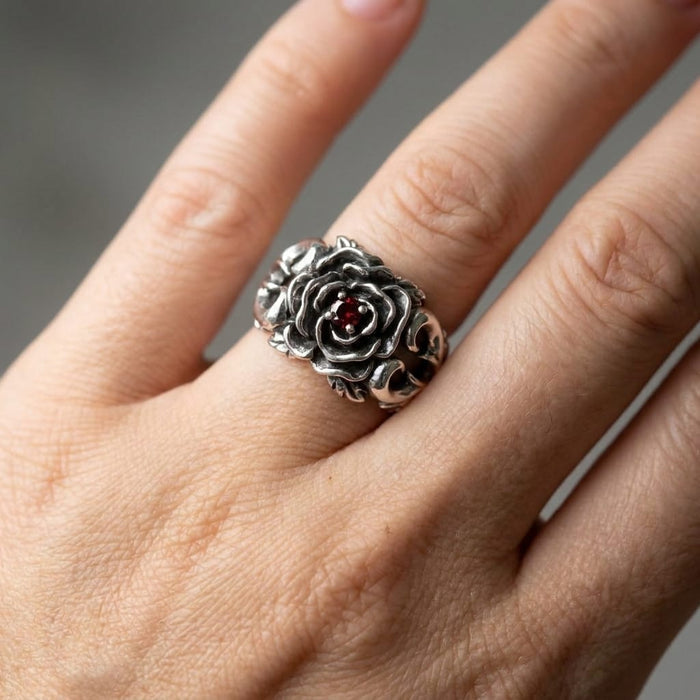 Hand wearing antiqued silver rose ring with red garnet center, showing fit and gothic floral styling on the finger