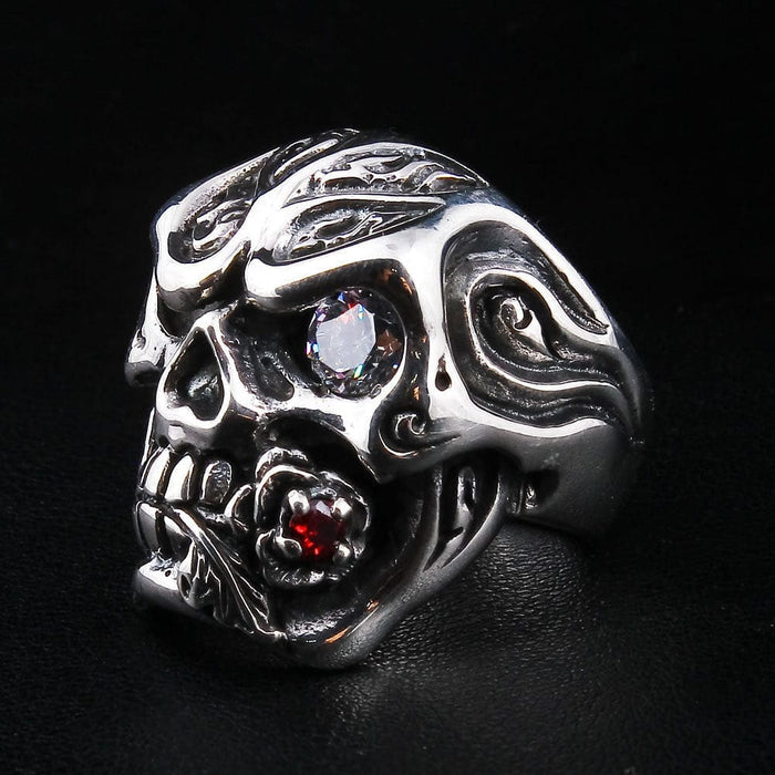 A close-up of the gothic skull ring, highlighting the red garnet stone set within the rose clenched in the skull's teeth.