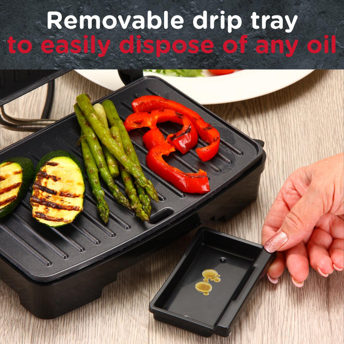Black grill with vegetables and a removable drip tray on a wooden surface. - Buy Now Panini Press, Sandwich Toaster & Health Grill