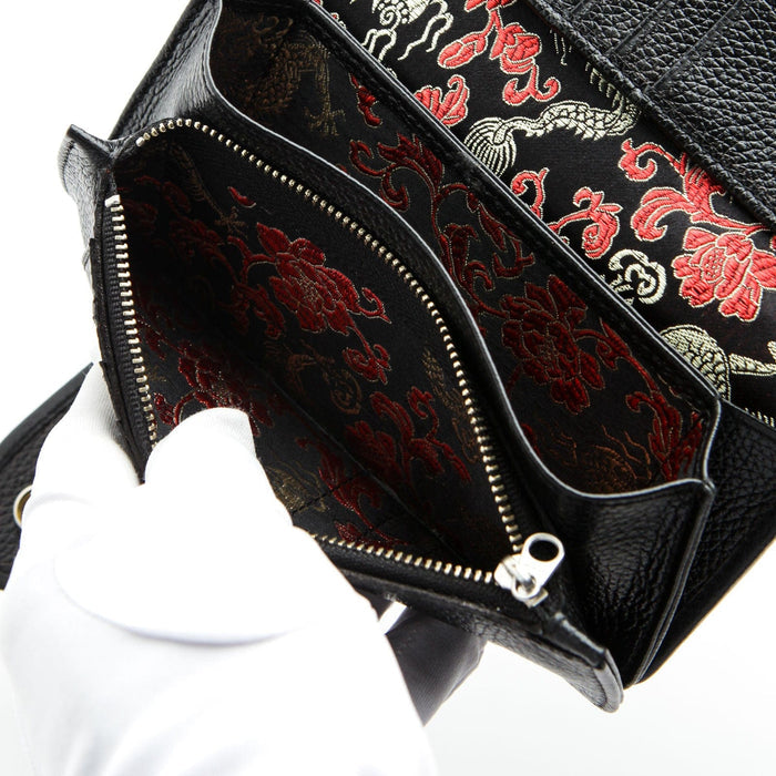 The interior of a black leather biker wallet showing a hidden, luxurious red and black emperor dragon silk lining in the zip pocket.