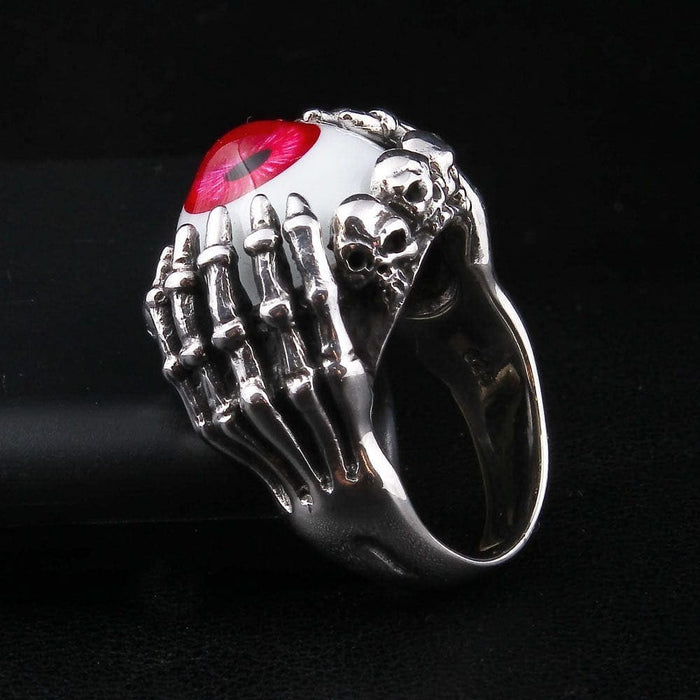 Side profile of gothic sterling silver ring showing skull details and skeletal fingers holding red eye