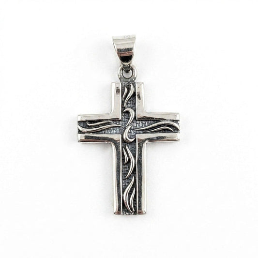Front view of a small sterling silver cross pendant featuring etched tribal pattern lines on a textured dark background.