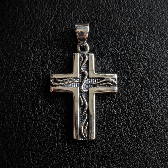 Flat lay of the small silver tribal pendant on black textured leather, emphasizing the polished borders and etched center.