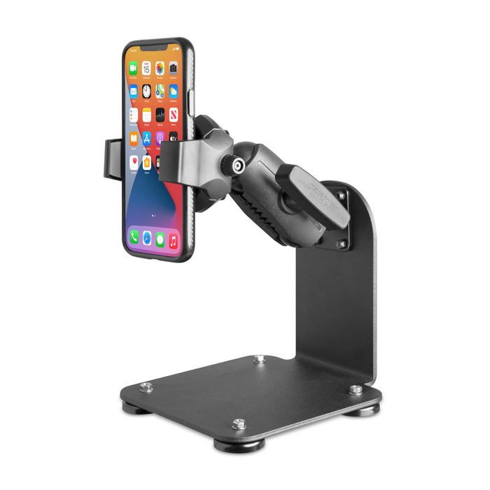 The SteadyMag™ Magnetic Mount System with RoadVise® Ultra Phone Holder is a black adjustable metal stand for warehouse vehicles, securely holding a smartphone upright. Its sturdy base has visible screws, padded feet, and the phone displays app icons.