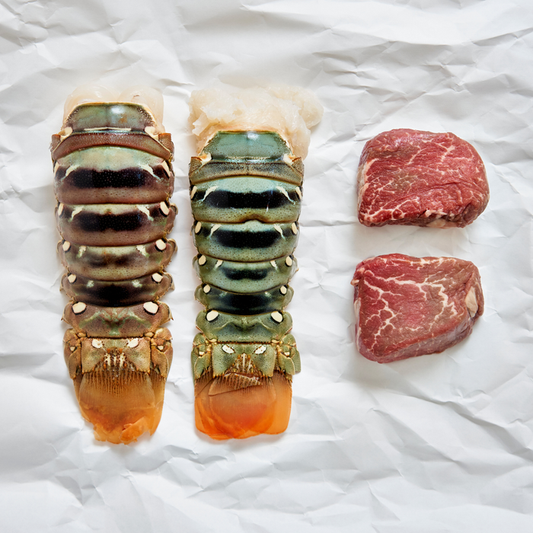 Two lobster tails and two pieces of raw steak on a white background