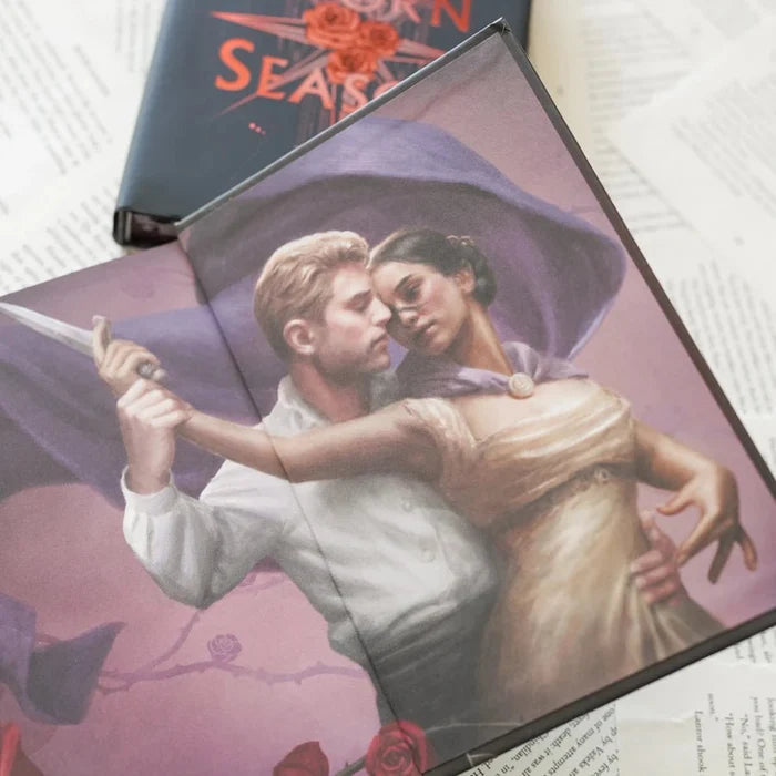 This image shows an open book displaying a dramatic illustration of a man and a woman in a passionate embrace. The man holds a knife, and both characters are dressed in period clothing, suggesting a historical or fantasy setting. The background features a large, purple flowing cape and a rose motif.