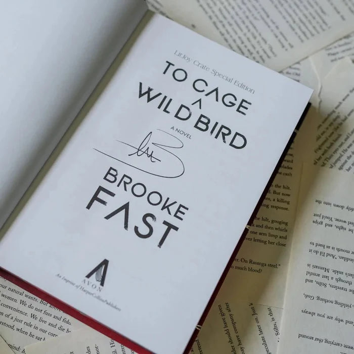 Signed title page of To Cage a Wild Bird LitJoy Crate Special Edition by Brooke Fast, showing the author's handwritten autograph in black ink above the author name and Avon HarperCollins publisher logo, laid on open book pages
