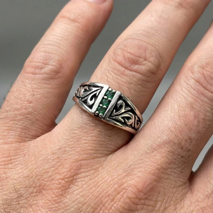 Mens Tribal Emerald Sterling Silver Ring worn on finger, featuring intricate tribal swirl carvings and a vertical row of green emerald stones
