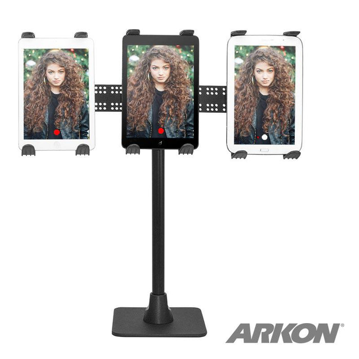 Three tablets on the TW Broadcaster TriStreamer Triple Tablet Holder 29-inch Stand, each showing a woman with long curly hair and a red streaming dot. The ARKON logo is at the bottom right.
