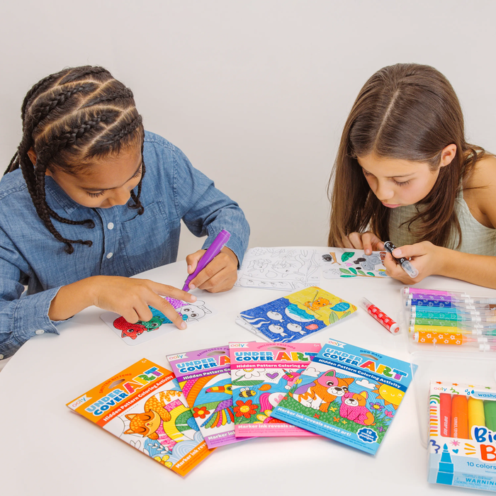 Two kids coloring art cards from the OOLY Undercover Art Hidden Pattern Coloring Activity Art Cards sets
