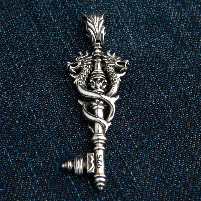 Detailed close-up of handcrafted Norse dragon key pendant in solid 925 sterling silver on denim background