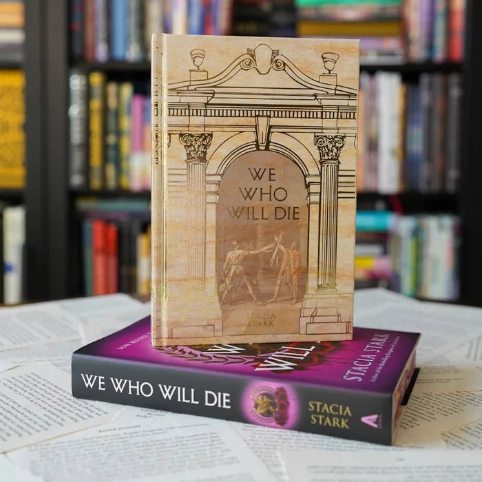 We Who Will Die LitJoy Edition exclusive alternate cover — cream hardcover with classical archway and column design by Stacia Stark, stacked on standard purple edition, from LitJoy Winter Romantasy TBR Box