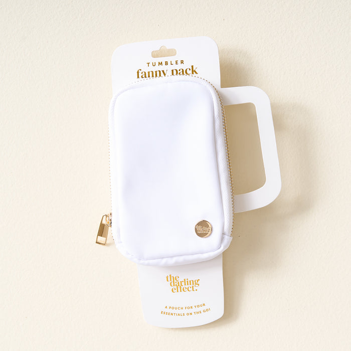 The Darling Effect White Tumbler Fanny Pack features gold text and a circular gold logo, attached to packaging. This water-resistant pouch is ideal for carrying your essentials on the go.