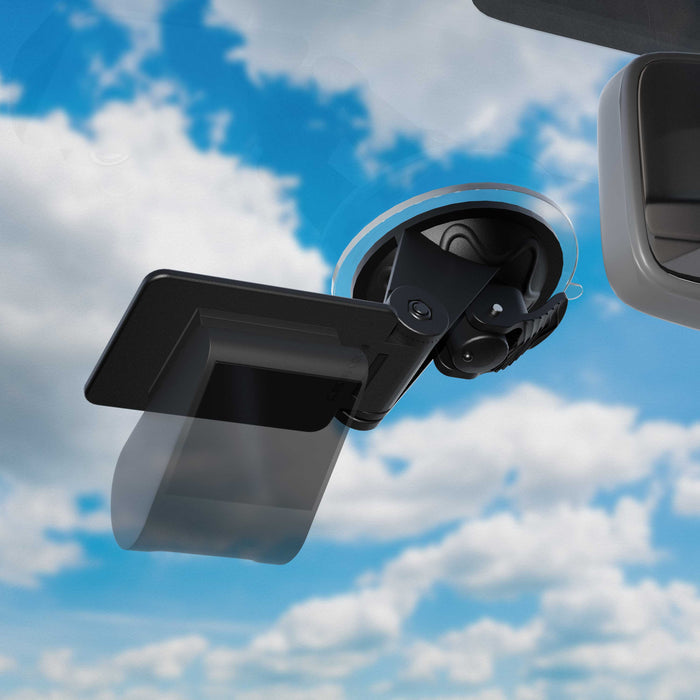 A close-up of a Windshield Suction Mount for EZ Pass Toll Transponders, Bluetooth GPS Receivers, and Radar Detectors attached to a car’s visor, with a bright blue sky and scattered clouds visible through the windshield.