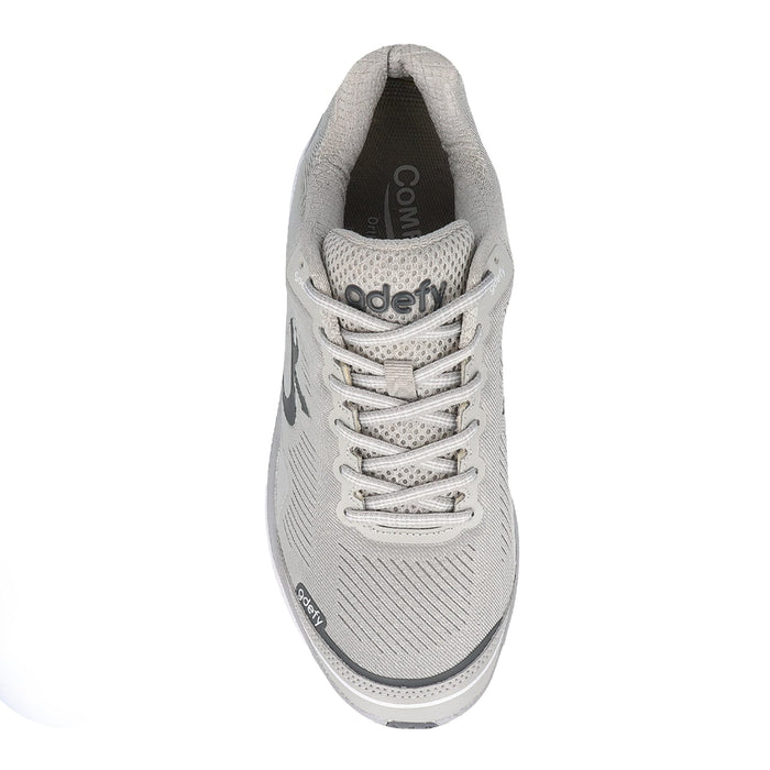 Light grey gdefy athletic shoe with a mesh upper, white laces, and textured fabric, shown from a top-down view.