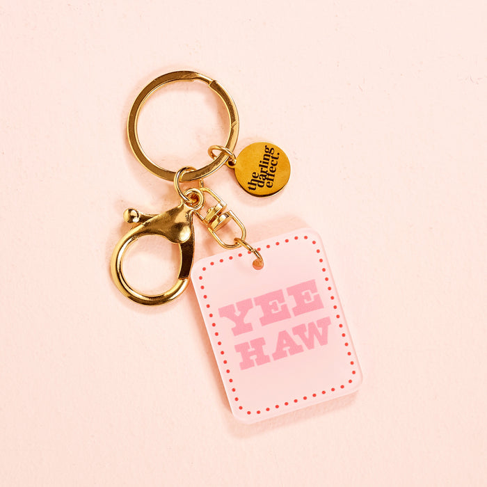 The Yeehaw Acrylic Keychain by the-darling-effect features a round “You’re doing great” charm and a pink YEE HAW tag—an adorable accessory for any fan of cute style.