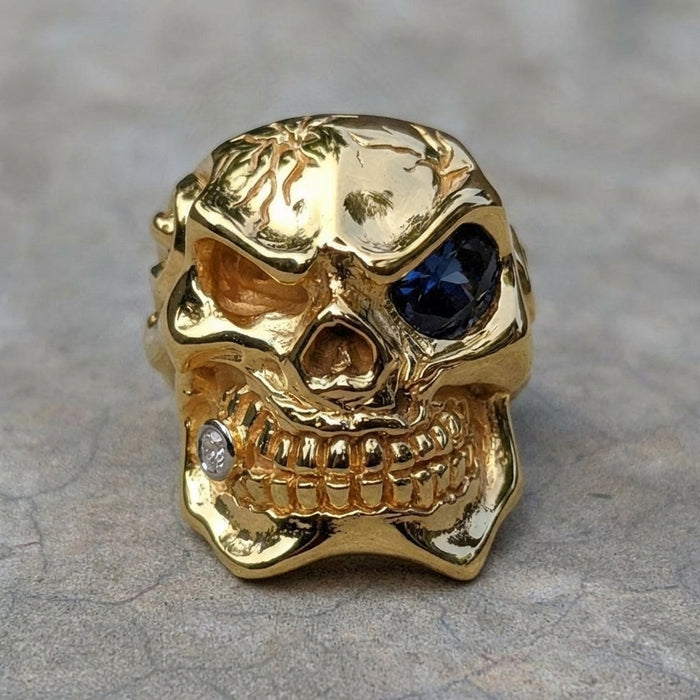 Front view of handcrafted 925 sterling silver skull ring with 14K gold plating featuring blue gemstone eye and diamond accent